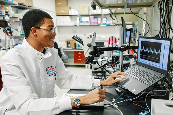 Researcher in a kinesiology lab analyzing data on laptop