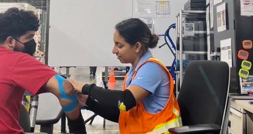 Valeria Zavala applies KT tape to an automotive worker's arm