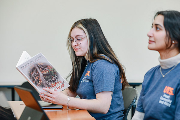 Students in class reading from their textbooks